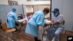 FILE - Nurses draw blood from patients during a COVID-19 antibody test drive at a church, in the Harlem neighborhood of the Manhattan, May 14, 2020.