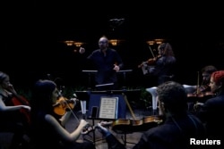 Spanish music director Hache Costa rehearses prior to performing an adaptation of Antonio Vivaldi's famous “The Four Seasons” concertos as a screen shows an image of flowers in spring in Madrid, Spain, October 24, 2023. (REUTERS/Susana Vera)