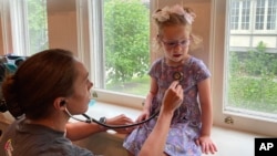 Courtney Chase, a nurse at Cincinnati Children's Hospital Medical Center, listens to 4-year-old Brynn Schulte's heart before the girl gets an infusion of medication to treat a rare genetic bleeding disorder, Aug. 3, 2023, in Cincinnati, Ohio. (AP Photo/Laura Ungar)