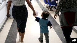 Maria Orbelina Cortez, right, walks with her 3-year-old son, Julio, center, and a worker at the Catholic Charities shelter in McAllen, Texas, Jan. 11, 2019. 