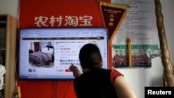 FILE - A customer points at a screen displaying a website of Alibaba's Taobao at a rural service center in Yuzhao Village, Tonglu, Zhejiang province, China, July 20, 2015. 