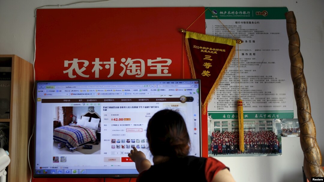FILE - A customer points at a screen displaying a website of Alibaba's Taobao at a rural service center in Yuzhao village, Tonglu, Zhejiang province, China, July 20, 2015. 