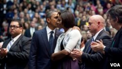 A la izquierda, Daniel Hernández aplaude, mientras el presidente Obama abraza a la primera dama Michelle Obama, con el esposo de Giffords, Mark Kelly y la secretaria Janet Napolitano a la dderecha en la foto.