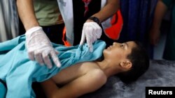 FILE- A boy is treated by medical staff after sustaining injuries from an explosion, at the Shifa hospital in Gaza City, August 8, 2014.