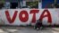 A man rests near a sign that reads 'vote' on a street in Comas on the outskirts of Lima, Peru, March 4, 2016. 