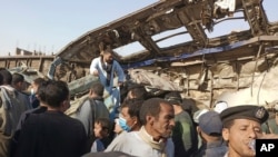 Un policía egipcio bebe agua mientras residentes del área buscan víctimas entre los restos de un tren descarrilado en Sohag, Egipto, el viernes, 26 de marzo del 2021.