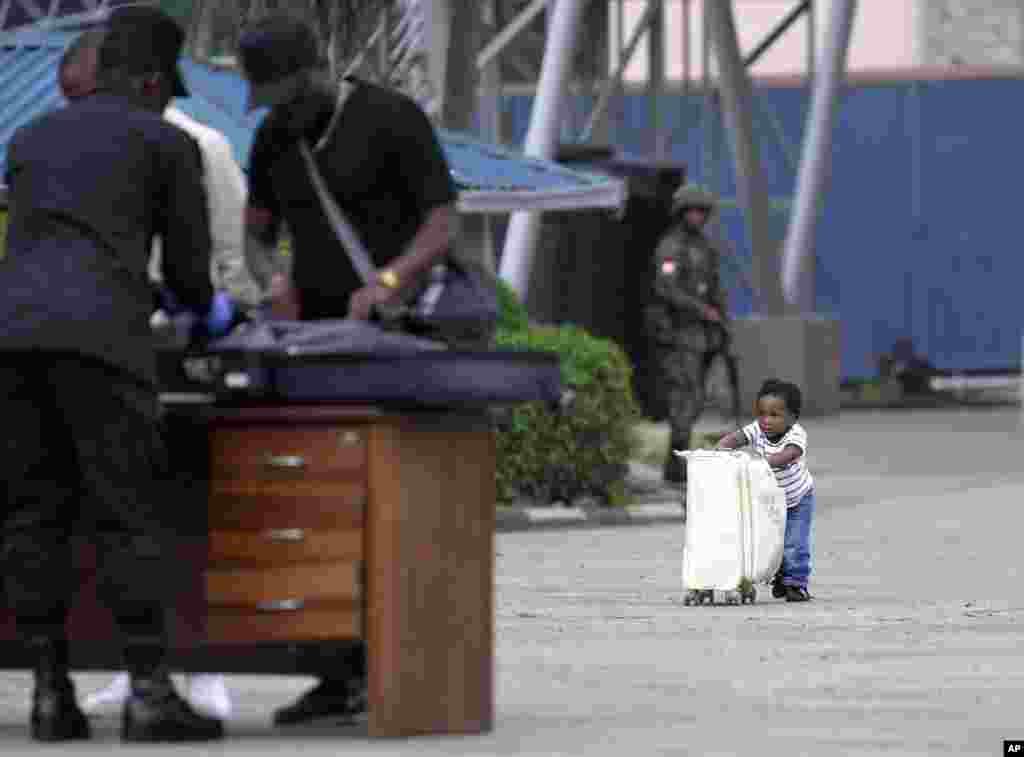 A child pushes a suitcase towards Rwanda security officials checking people crossing from Congo in Gisenyi, Rwanda, following M23 rebels&#39; advances into eastern Congo&#39;s capital Goma.