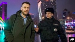 FILE - Alexei Navalny, shown being detained by a policeman after violating a house arrest order in January, says either state security services or a "pro-government organization" was behind the killing of Boris Nemtsov.