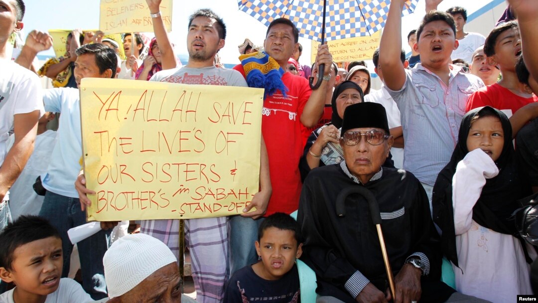 Former Sultan of Sulu Jamalul Kiram III (seated at R) with his followers display placards in front of Blue Mosque in Maharlika village, Taguig city, south of Manila, March 1, 2013
