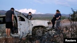 FILE - Relatives of slain members of Mexican American families belonging to Mormon communities observe the burned wreckage of a vehicle where some of their relatives were killed, in Bavispe, Sonora state, Mexico, Nov. 5, 2019.