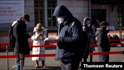 성탄절인 25일 한국 서울역에 설치된 신종 코로나바이러스 임시선별진료소에서 주민들이 코로나 감염 검사를 받기 위해 줄 서 있다.