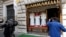 FILE - TV crews film Gammarelli tailoring shop window where three sets of papal outfits - small, medium and large sizes - which will be sent to the Vatican for the new pope, are displayed, in Rome.