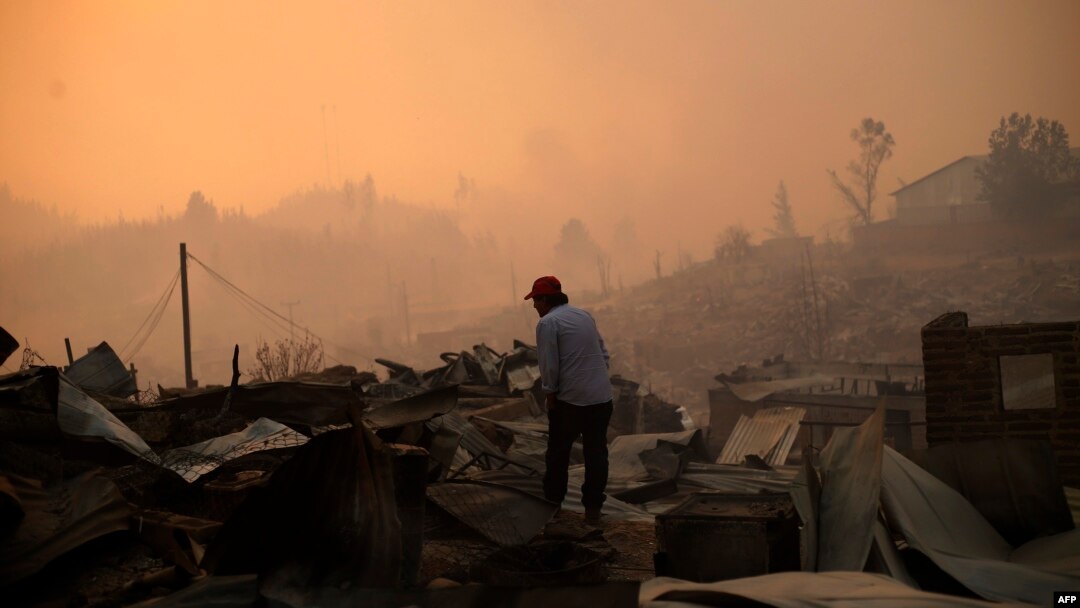 A man stands amid the remains of a burnt house after a forest fire devastated Santa Olga, 240 kilometres south of Santiago, Jan. 26, 2017.