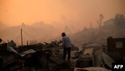 A man stands amid the remains of a burnt house after a forest fire devastated Santa Olga, 240 kilometres south of Santiago, Jan. 26, 2017.