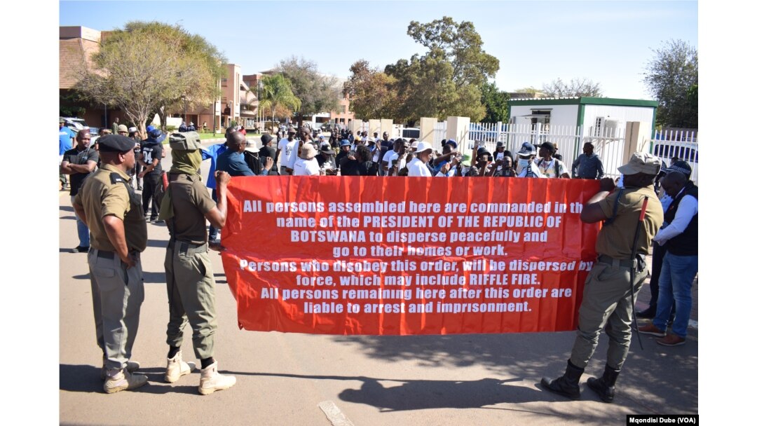 Botswanan police officers carry a banner warning protesters to vacate the National Assembly premises in Gaborone, Botswana, on Sept. 4, 2024.