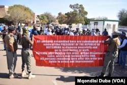 Botswanan police officers carry a banner warning protesters to vacate the National Assembly premises in Gaborone, Botswana, on Sept. 4, 2024.