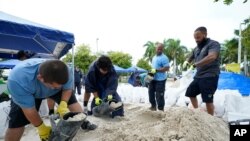 City workers fill sandbags at a drive-thru sandbag distribution event for residents ahead of the arrival of rains associated with tropical depression Fred, Aug. 13, 2021, at Grapeland Park in Miami.