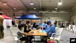 In this photo provided by the Australian Defence Force evacuees from Afghanistan are processed after arriving at Australia's main base in the Middle East region, Aug. 18, 2021, according to Australian defense. 
