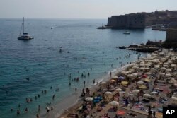 Wisatawan menikmati suasana di pantai Dubrovnik, Kroasia, 13 Agustus 2021. (Darko Bandic/AP)