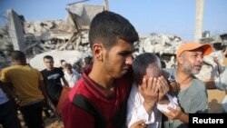 Seorang pria Palestina menangis, sementara warga lainnya mencari korban di antara reruntuhan setelah serangan udara Israel di sebuah permukiman di Rafah, Jalur Gaza (29/7).