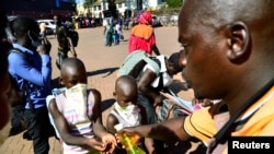 Wasafiri wakiwekewa sanitizer kabla ya kupanda mabasi katika kituo cha basi mjini Kampala, Uganda ikiwa ni kujilinda na virusi vya corona, Machi 24, 2020.Picture taken March 24, 2020. REUTERS/Abubaker Lubowa NO RESALES. NO ARCHIVES