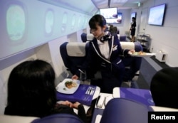 Seorang pramugari menyajikan makanan pembuka kepada para tamu "First Airlines", penerbangan kelas satu realitas maya di Tokyo, Japan, 14 Februari 2018.