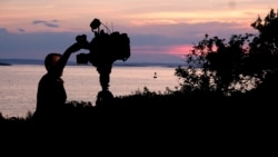 A member of a TV crew adjusts their camera while filming near the shore of Bailey Island, Maine, where a woman swimming off the coast was killed in an apparent shark attack Monday, July 27, 2020. (AP Photo/Jim Gerberich)