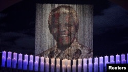 Lilin-lilin belasungkawa mengelilingi foto Nelson Mandela di desa kelahirannya, Qunu, 15 Desember 2013.