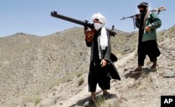 FILE - Members of a breakaway faction of the Taliban fighters walk during a gathering, in Shindand district of Herat province, Afghanistan.