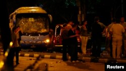 Officials stand around a bus with a smashed windshield following a riot in Singapore's Little India district, Dec. 9, 2013.