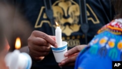 People hold candles at a vigil for Alton Sterling, who was shot and killed by a police, outside the Triple S convenience store in Baton Rouge, Louisiana, July 6, 2016.