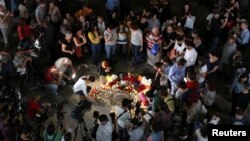 People bring flowers and candles during a gathering in memory of singer Charles Aznavour, who died aged 94, in Charles Aznavour Square in Yerevan, Armenia, Oct. 1, 2018.