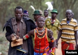 A man holds onto a girl as he brings her back to her family home after she tried to escape when she realized she is to be married, about 80 km (50 miles) from the town of Marigat in Baringo County, Dec. 7, 2014.