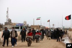 FILE - Afghans return to Afghanistan at the Islam Qala border with Iran, in the western Herat province, Feb. 20, 2019. Security officials worry that Iranian-backed Afghan veterans of the war in Syria will one day become a secret army for Tehran in Afghanistan itself.