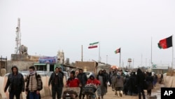 FILE - Afghans return to Afghanistan at the Islam Qala border with Iran, in the western Herat province, Feb. 20, 2019. 