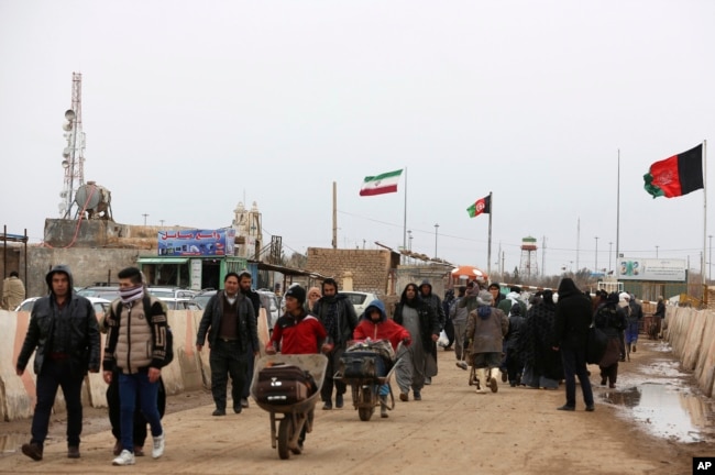 FILE - Afghans return to Afghanistan at the Islam Qala border with Iran, in the western Herat province, Feb. 20, 2019. Security officials worry that Iranian-backed Afghan veterans of the war in Syria will one day become a secret army for Tehran in Afghanistan itself.