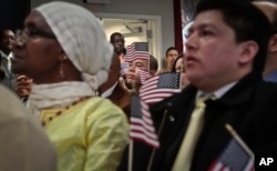 FILE - Immigrants hold miniature U.S. flags during a naturalization ceremony in New York. In a major shift in immigration patterns over the next 50 years, While Europeans dominated immigration in the 1910s, as Latin Americans did after 1970, Asians are now the latest and largest wave of newcomers to the United States, the Brookings Institution reported.