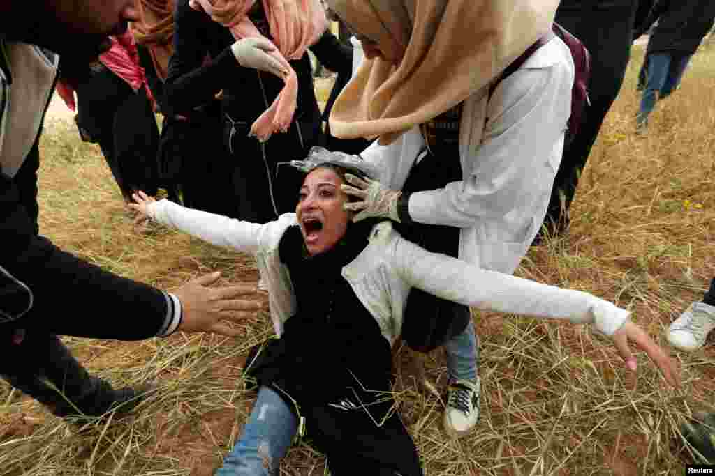 A Palestinian woman reacts after inhaling tear gas fired by Israeli forces during a protest marking Land Day and the first anniversary of a surge of border protests, at the Israel-Gaza border fence, in the southern Gaza Strip, March 30, 2019.