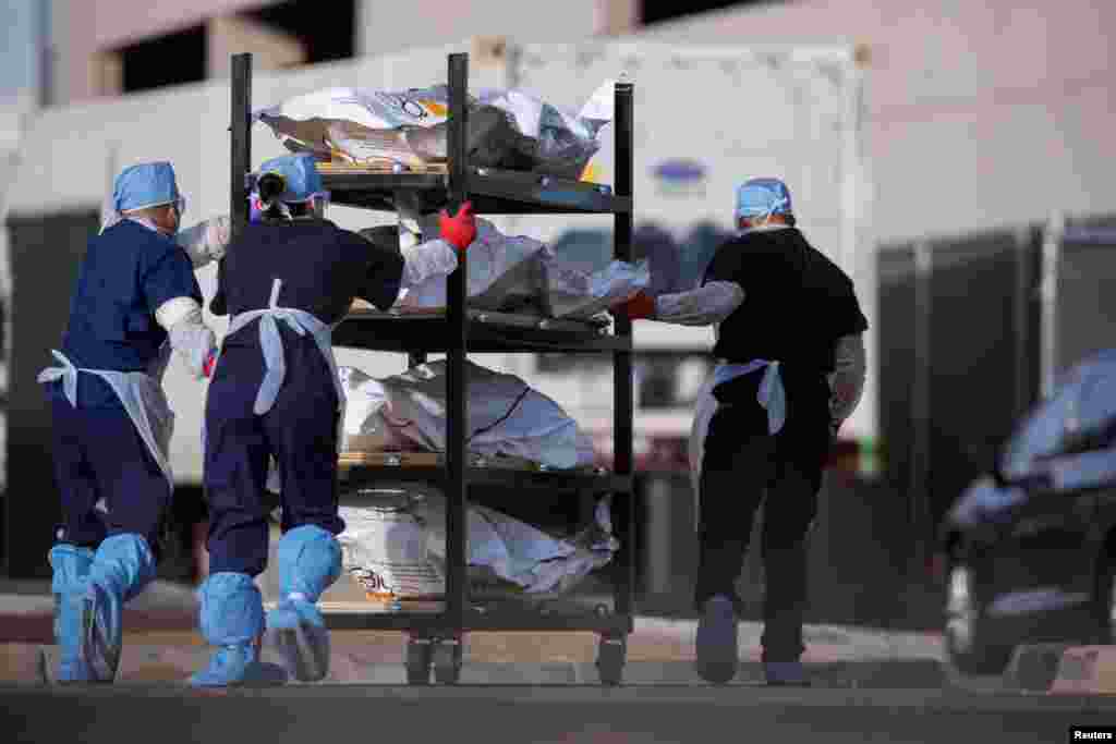 El Paso County Medical Examiner&#39;s Office workers roll bodies that are in bags labeled &quot;COVID&quot; from cold transportation vehicles into the morgue office, during the ongoing COVID-19 crisis, in El Paso, Texas, November 23, 2020.