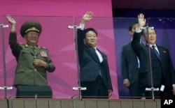 N. Korea’s National Defense Commission Vice Chairman Hwang Pyong So, left, and N. Korea’s Workers Party secretaries, Choe Ryong Hae and Kim Yang Gon wave as their team marches into the stadium at Asian Games in Incheon, S. Korea, Oct. 4, 2014.