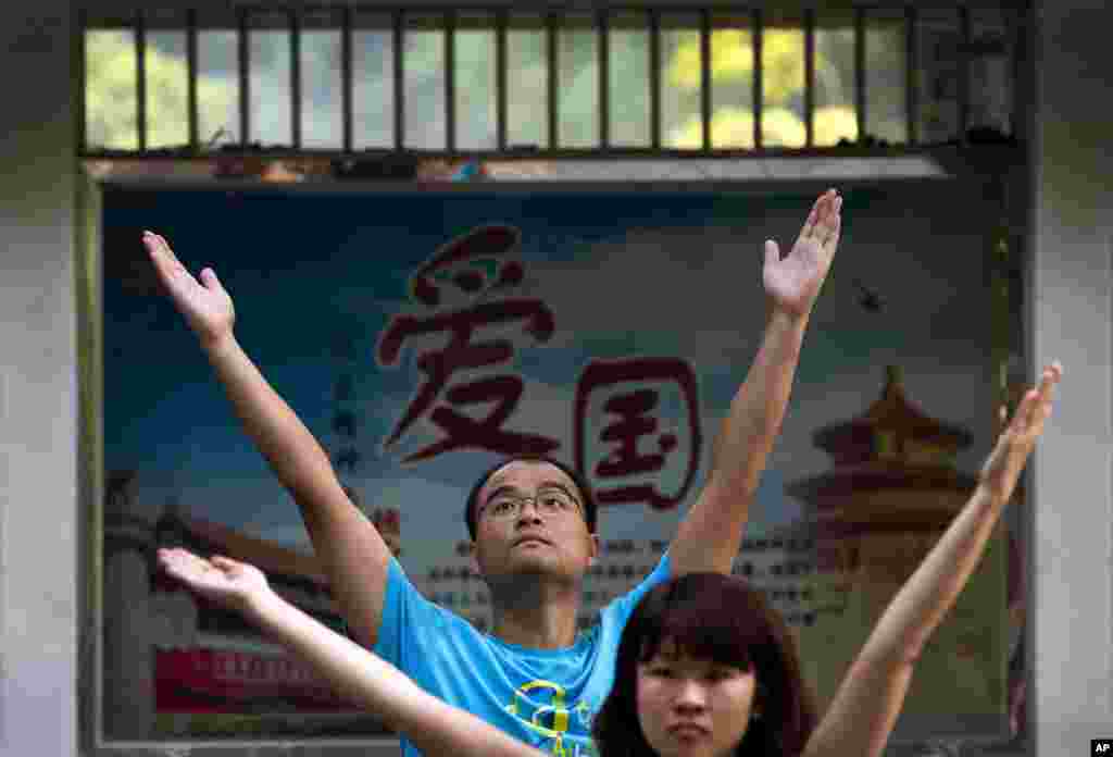 Employees of a Chinese bank take part in a motivation exercise at Ritan Park in Beijing. The word of a propaganda poster, background, reads &quot;Patriotism.&quot; 