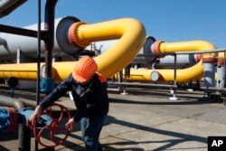 FILE - A Ukrainian worker operates a valve at an underground gas storage facility in Strij, outside Lviv, Ukraine, May 21, 2014.