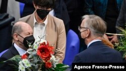 Designated German Chancellor Olaf Scholz (L) is offered flowers by Parliamentary group co-leader "Die Linke" after being elected as Germany's new Chancellor in Berlin on Dec. 8, 2021.
