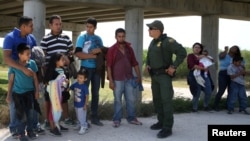 FILE - Border patrol agent Sergio Ramirez talks with immigrants who illegally crossed the border from Mexico into the U.S. in the Rio Grande Valley sector, near McAllen, Texas, April 2, 2018. 
