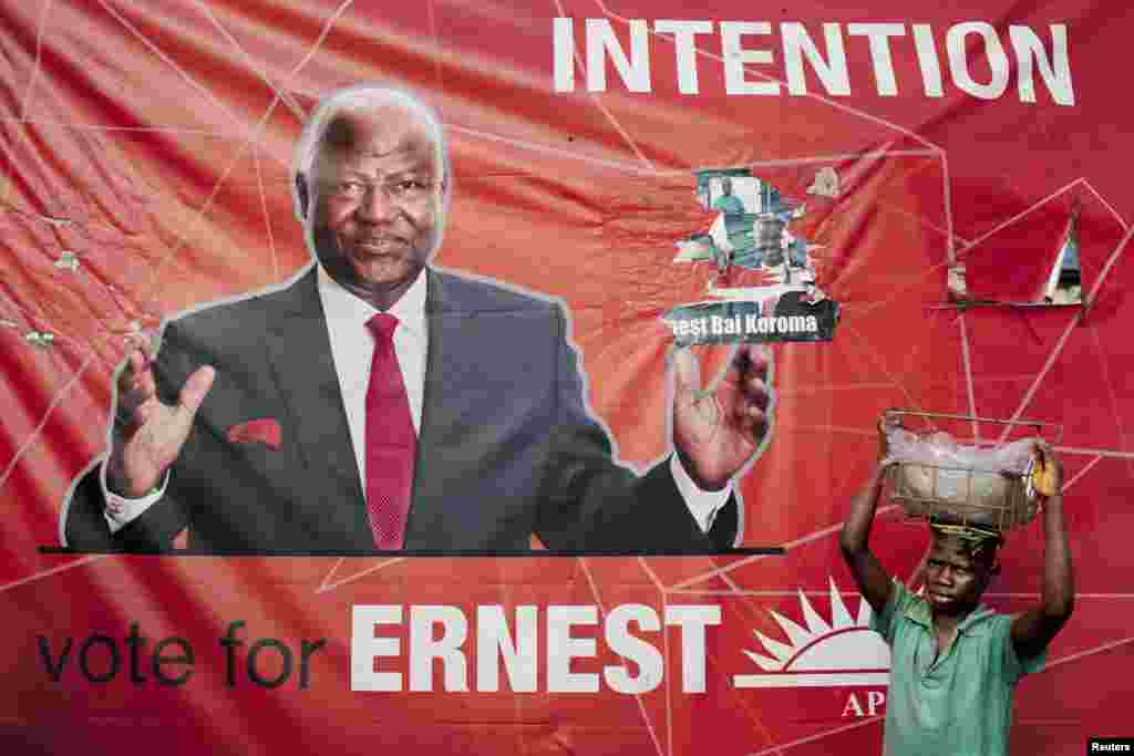 A child street vendor stands in front of a poster for Sierra Leone's ruling party presidential candidate Ernest Bai Koroma, Freetown, Nov. 16, 2012.