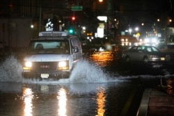 Magari yakijaribu kupita mitaa iliyojaa maji yakiyakwepa magari yaliyo kwama na kuachwa barabarani huko Teterboro, New Jersey, Alhamisi, Sept. 2, 2021. (AP Photo/Seth Wenig)