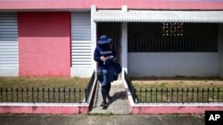 Postal worker Jose Montoya does his rounds in Carolina, Puerto Rico, Thursday, Oct. 1, 2020. More than half of all homes in Puerto Rico lack a physical address, so the absence of street names and numbers also have created multiple problems. (AP Photo/Carlos Giusti)