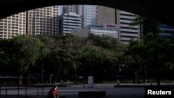 Seorang pria mengenakan masker berdiri di luar gedung Bursa Efek Filipina di kawasan bisnis, di Makati City, Metro Manila, Filipina, 17 Maret 2020. (Foto: Reuters)