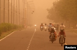 FILE - Commuters make their way amidst haze and dust in Chandigarh, India, June 15, 2018.