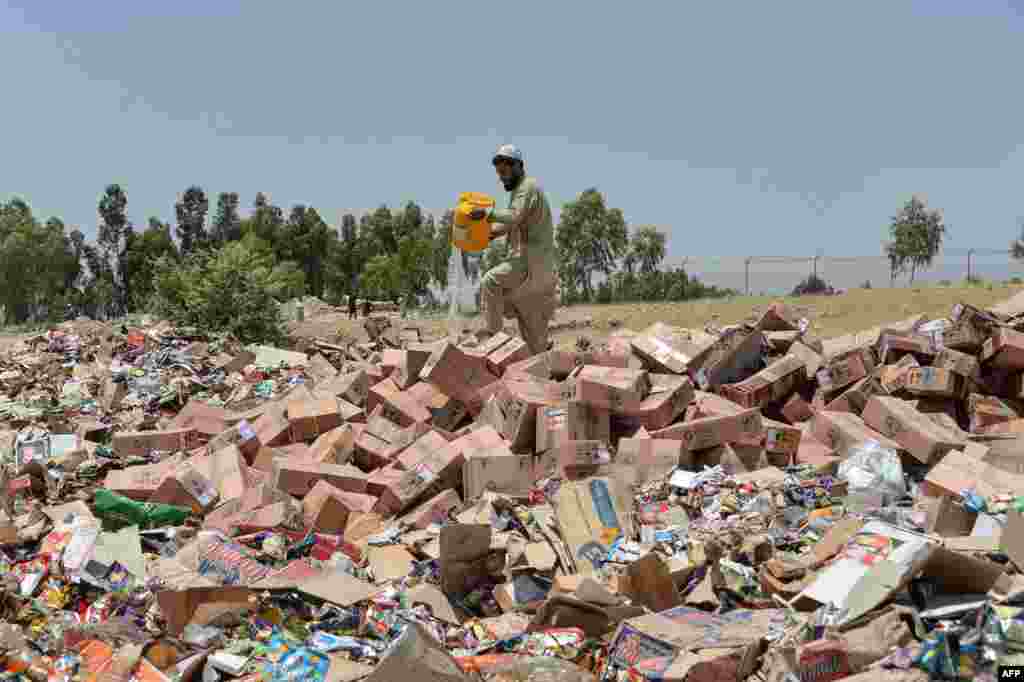 A health worker pours gasoline on expired medicines collected from different hospitals as he prepares to set them alight on the outskirts of Jalalabad, Afghanistan.